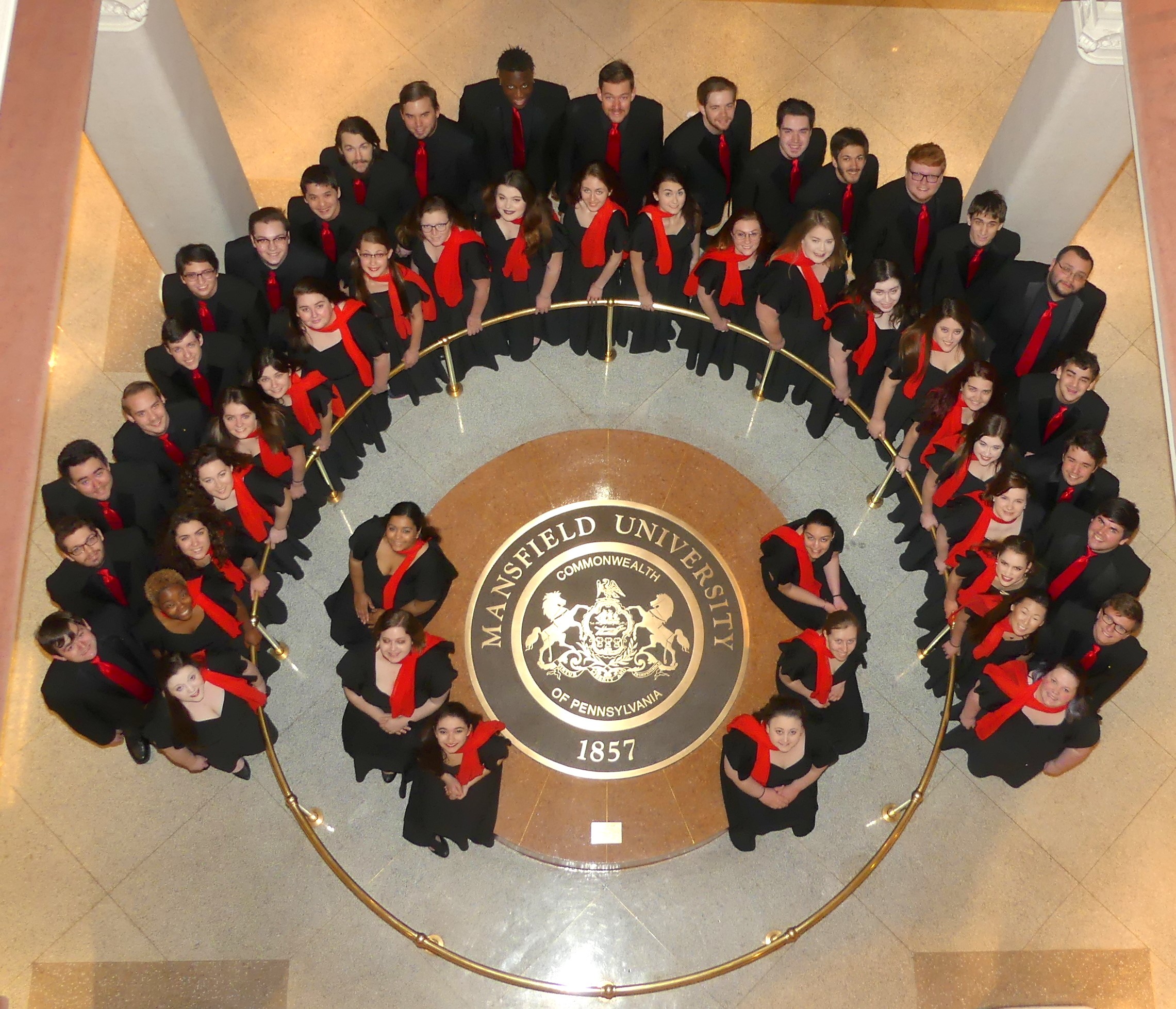 Choir standing around university seal